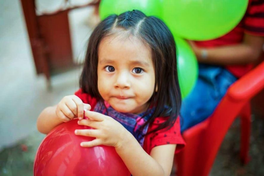 Une petite fille serre un ballon rouge