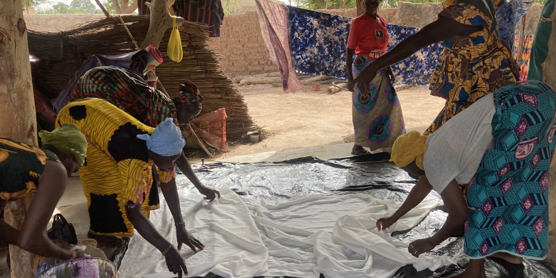 Image de femmes étalant des draps au sol.