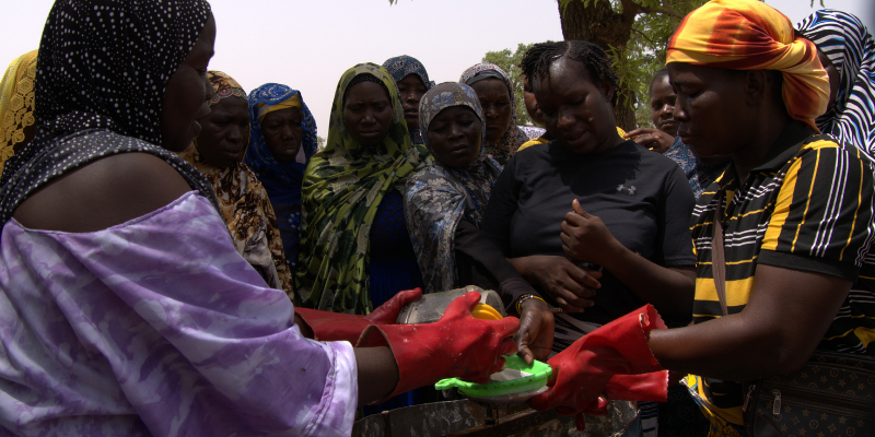 Image de femmes participant à une démonstration pratique autour d'un équipement agricole.
